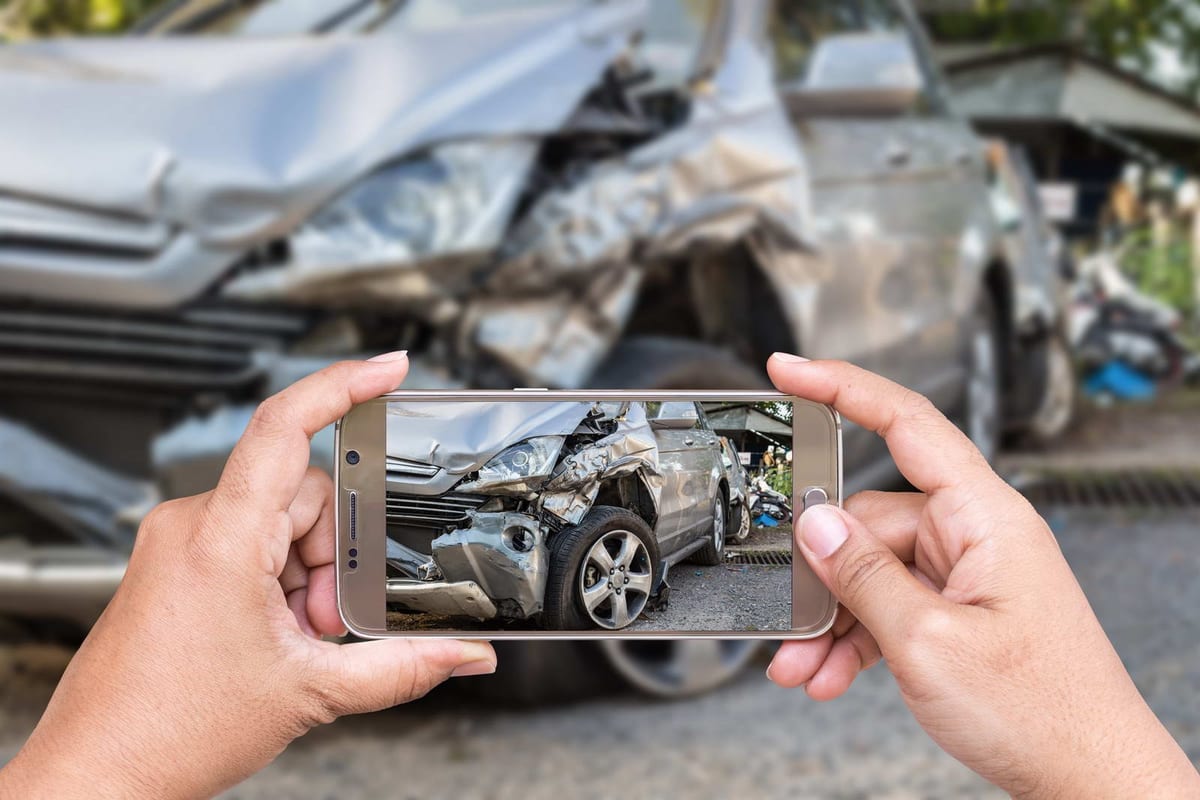 A damaged car being photographed after a collision