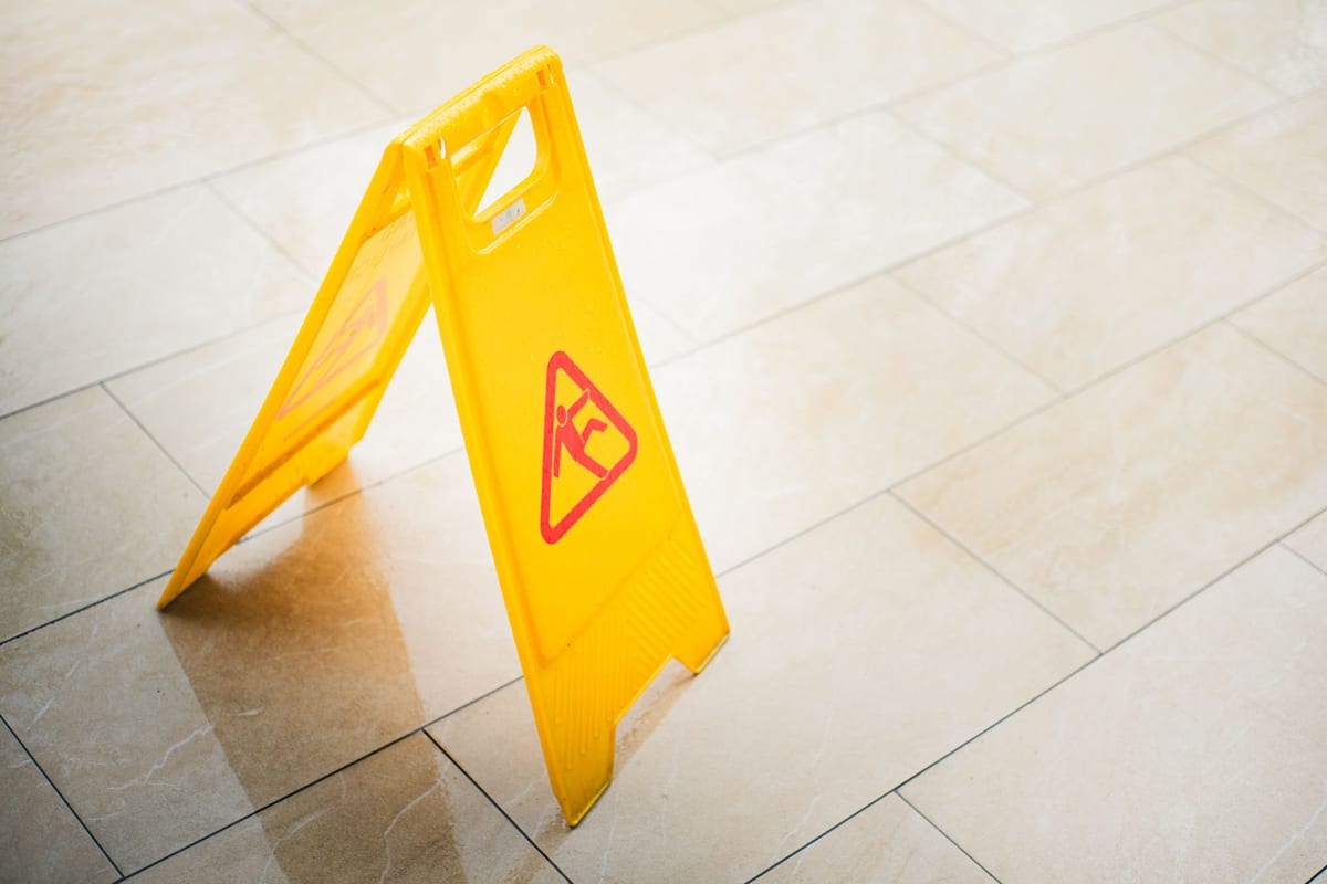A wet floor caution sign on a tiled floor
