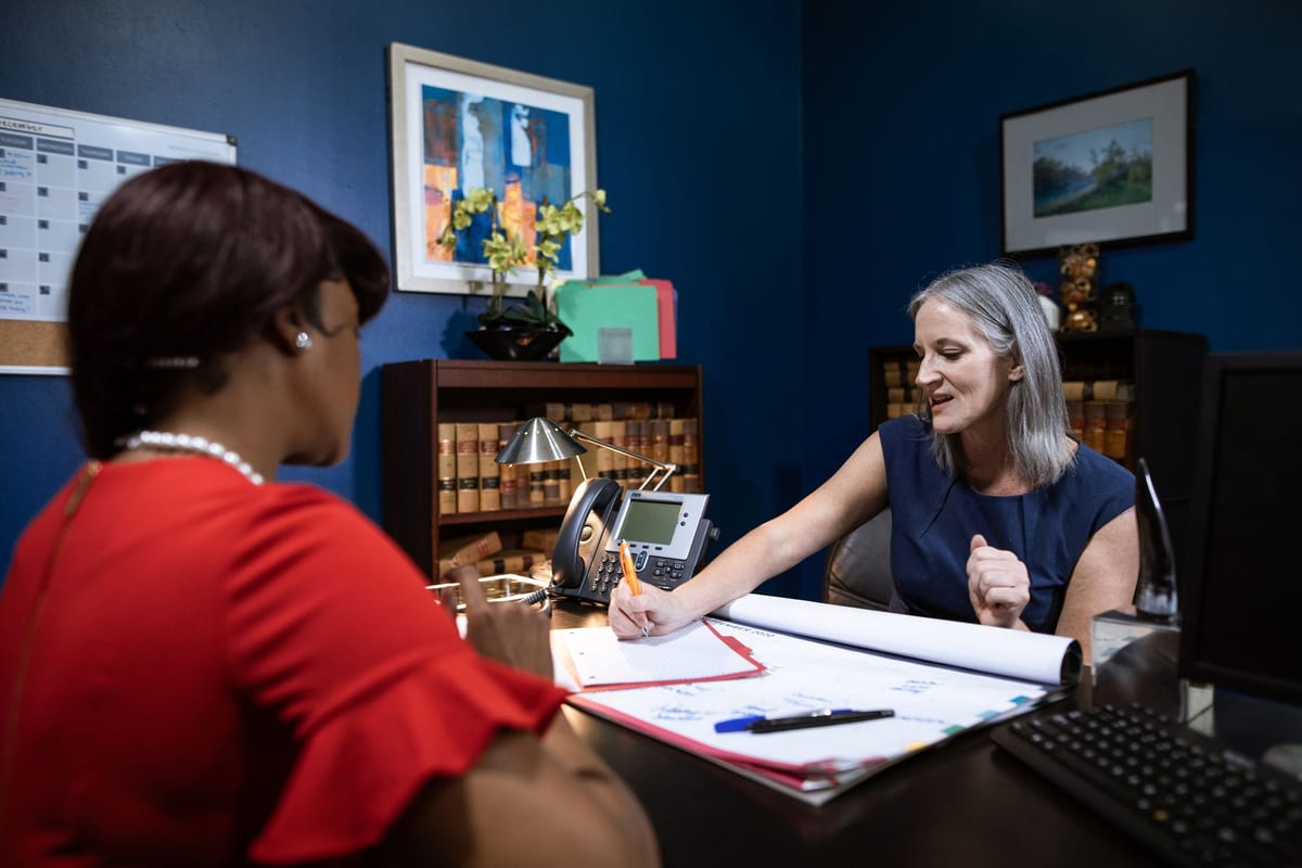 A lawyer meeting with a client in a book-lined office